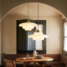 a dining room table with four lights hanging over it