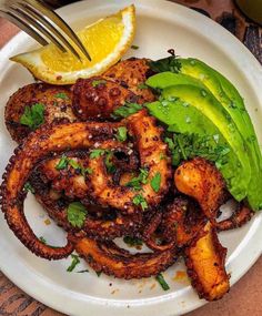 a plate with octopus rings, avocado and lemon wedges