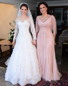 two women standing next to each other in wedding gowns and holding hands with one another