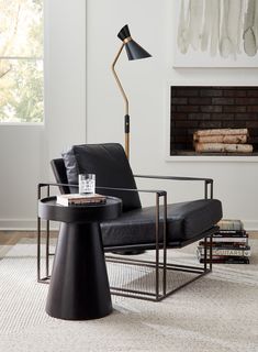 a living room with a black chair and a lamp on the table next to it