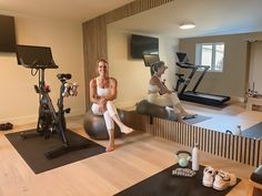 two women sitting on exercise balls in a gym with treadmills and stationary bikes