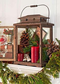 a lantern with pine cones and evergreens on the mantle