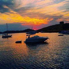 boats are floating in the water at sunset