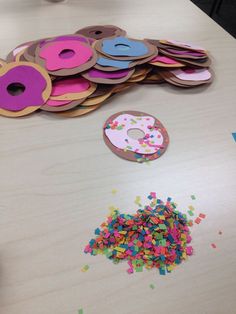 a table topped with lots of doughnuts and sprinkles next to a donut