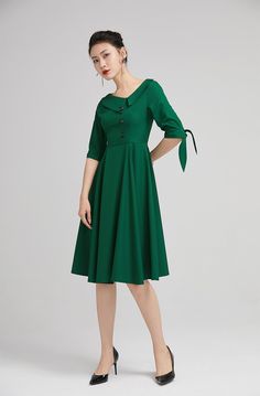 "The green swing dress with lapel collar is made of high quality polyester. The full cut romantic knee-length skirt with pleating details sways gently with every step. The tailored fitted bodice with a hidden side zip, defines the bust and waist. The elbow length sleeves are finished off with tie belt cuff. A row of buttons in the front and the Lapel Collar gives our classic dress timeless vintage charm, striking just the right balance between elegance and comfort. DETAILS * Satiny fabric, conta Fit And Flare Midi Dress, Midi Dress Vintage, Vintage Midi Dress, African Print Dress Ankara, Vintage Midi Dresses, Handmade Skirts, Custom Dress, Wool Clothing, African Print Dress