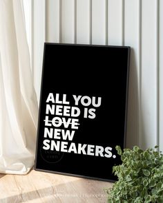 an all you need is love and new sneakers poster next to a potted plant