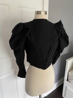 1900s black button sleeve corseted blouse. Fabulous capped sleeves with black beading details. Sturdy, but not perfect - large stains on the lining and lots of moth holes in the wool exterior, mainly on one shoulder and center front. Stain on that same shoulder. hook and eye closures, missing 2 hooks, one inch rip in the brown lining on the lower back by the hook and eyes. women's XS 34" bust 25" waist 16.25" shoulder to hem 12.5" back shoulders Black Vintage Overbust Corset, Gothic Blouse Victorian, Black Victorian Blouse, 1900s Blouse, Blouse Corset, Black Gothic V-neck Top, Mutton Sleeve, Corset Blouse, Womens Blouses