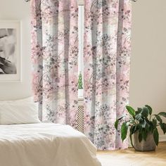 a white bed sitting next to a window covered in pink curtains