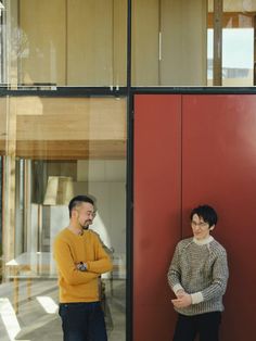 two people standing in front of a red door