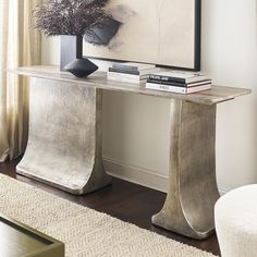 a modern console table with books on it and a painting in the corner behind it