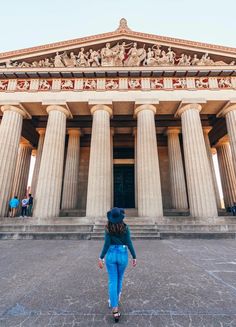 a woman walking in front of a building with columns