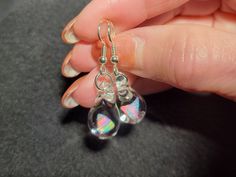 "Make a splash with these Mermaid's Tears earrings!  These gorgeous hand-blown teardrop earrings are made with only the highest quality borosilicate glass and features a mesmerizing Gilson opal polished nugget that shimmers with blue, green, yellow, and even a hint of red within the opal encased in glass. These earrings come mounted on sturdy sterling silver fish hooks, perfect for those with sensitive ears. And with a heavy gauge sterling that won't bend out of shape, you can wear these earrings with confidence knowing they'll stay securely in place. Measuring .85\" x .5\", these earrings dangle 1.5\" for a perfect statement for those who love unique jewelry.   Plus, with a gift box included, they're ready for gift giving or treating yourself to a special accessory. Don't forget to look a Nickel-free Glass Drop Jewelry, Nickel-free Teardrop Glass Jewelry, Nickel-free Glass Teardrop Jewelry, Hypoallergenic Teardrop Glass Jewelry, Glass Teardrop Jewelry With Matching Earrings, Glass Drop Earrings With Matching Set, Hypoallergenic Glass Teardrop Jewelry, Glass Drop Earrings As Gift, Nickel-free Teardrop Glass Earrings