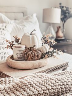 a tray with pumpkins, candles and other fall decorations on top of a bed