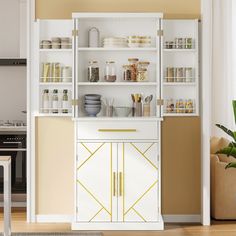 a white cabinet with gold trim and glass doors in a living room next to a potted plant