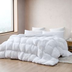 a large white comforter sitting on top of a wooden floor next to a window