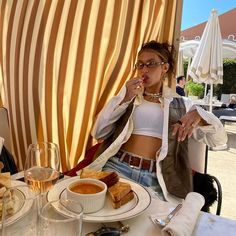 a woman sitting at a table with food and drinks in front of her, eating