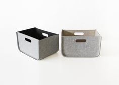 two storage bins sitting side by side on a white surface, one is grey and the other is gray