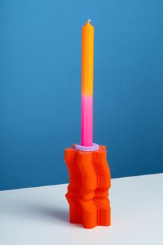 an orange and pink candle holder sitting on top of a table