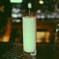 a tall glass filled with liquid sitting on top of a table