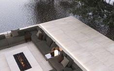 an aerial view of a living room with couches and fire pit next to water