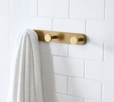 a towel is hanging on the wall next to a towel rack and white brick walls