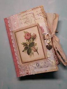 an open book with a rose on it and some tags attached to the front cover