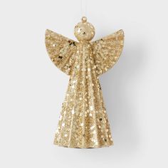 a gold angel ornament hanging from a string on a white wall with glitter