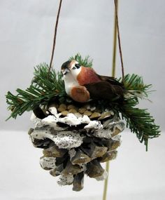 a bird sitting on top of a pine cone ornament hanging from a twig