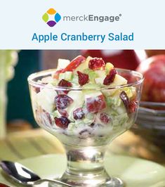 an apple cranberry salad in a glass bowl on a plate with a spoon