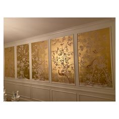 three panels with birds and flowers on them are hanging in front of a wall that has white paneling