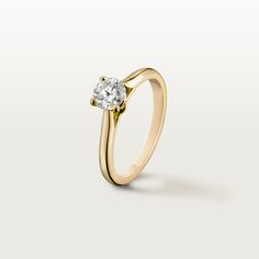 a yellow gold engagement ring with a single diamond in the center, on a white background