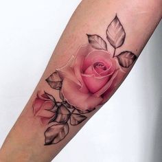 a pink rose tattoo on the left forearm and arm with leaves around it, in black ink