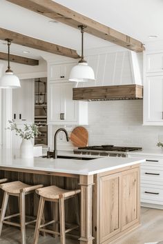 a kitchen with white cabinets and wooden stools next to an island in the middle