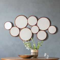 a vase filled with flowers sitting on top of a wooden table next to a wall mounted mirror