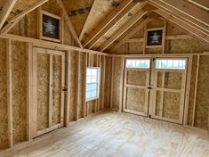 an empty room with wooden walls and windows in the center, surrounded by plywood