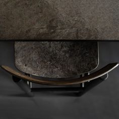 the back end of a table with a wooden base and metal legs, against a dark background