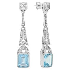 Top off your look with this spectacular pair of earrings. Coordinate them with your favorite outfit for a brilliant and lively appearance. The top of the solitaire drop earrings shows a beautiful cluster of round diamonds, in which the stunning spray design gently dangles below with the emerald cut blue topaz. Information Metal: 14K White Gold Width: 9 mm. Length: 50 mm. Weight: 9.18 g. (approx. in total) Backing: Push Back Center Gemstones Type: Blue Topaz Shape: Emerald Size: 10x8 mm. Number: Formal Blue Topaz Diamond Earrings Fine Jewelry, Formal Blue Topaz Diamond Earrings, Dazzling Diamond Gemstone Earrings For Formal Occasions, Dazzling Diamond Gemstone Earrings For Formal Events, Elegant Blue Diamond Cut Earrings, Formal White Gold Earrings With Blue Topaz, Elegant Blue Diamond Dangle Earrings, Luxury Blue Topaz Drop Earrings, Formal Platinum Earrings With Gemstone