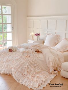 a white bed with ruffled sheets and pillows