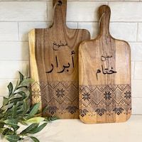 two wooden cutting boards with arabic writing on them