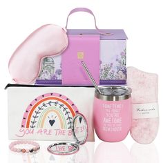 the contents of a pink gift box including a cup, travel mug and other items