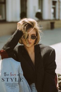 a woman sitting on the ground with her hand in her hair and sunglasses over her head