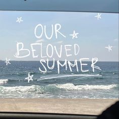 the words our beloved summer are written in white chalk on a blue sky over an ocean