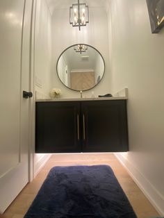 a bathroom with a blue rug on the floor and a large round mirror above it