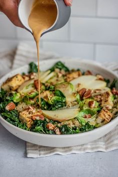 someone pouring dressing into a white bowl filled with vegetables