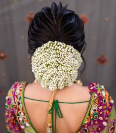 the back of a woman's head with white flowers on her face and hair