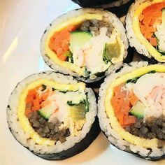 four sushi rolls with various vegetables and meats in them on a white plate