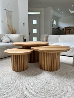 two circular wooden tables sitting on top of a carpeted floor next to couches