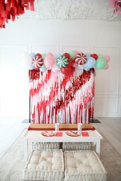 a table with some candy canes on it and balloons hanging from the ceiling above