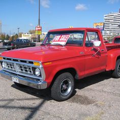 an old red pickup truck parked in a parking lot