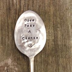 a spoon with the words give peas a chance written on it sitting next to a piece of wood